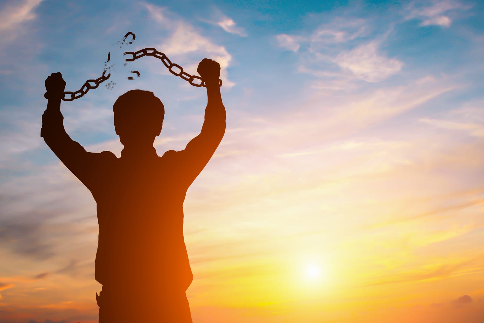 silhouette-image-of-a-businessman-with-broken-chains-in-sunset