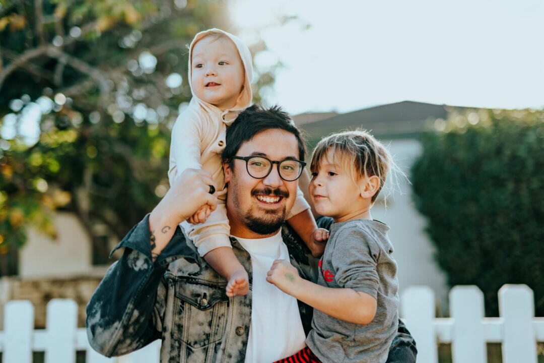 invōk.io petition & crowdfunding social platform - A man holding his two children in front of a white picket fence