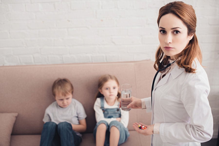 invōk.io petition & crowdfunding social platform - A woman is sitting on a couch with her children while reading a Critical Psychiatry Textbook.|invōk.io petition & crowdfunding social platform - A sign indicating a drug free and gun free school zone.
