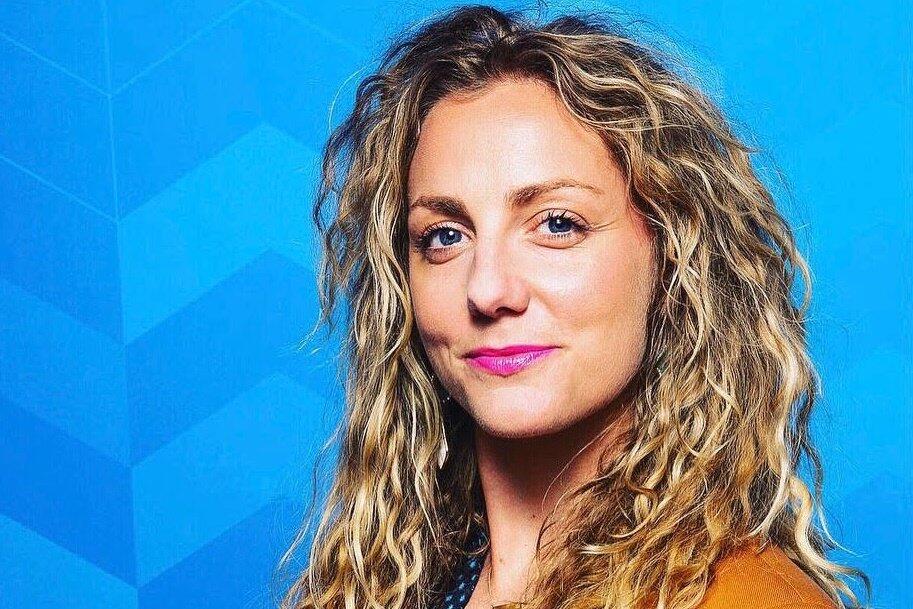 invōk.io petition & crowdfunding social platform - A woman with curly hair advocating on an invōk.io petition in front of a blue background.